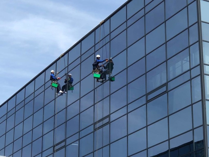 альпинисты моют стеклянный фасад